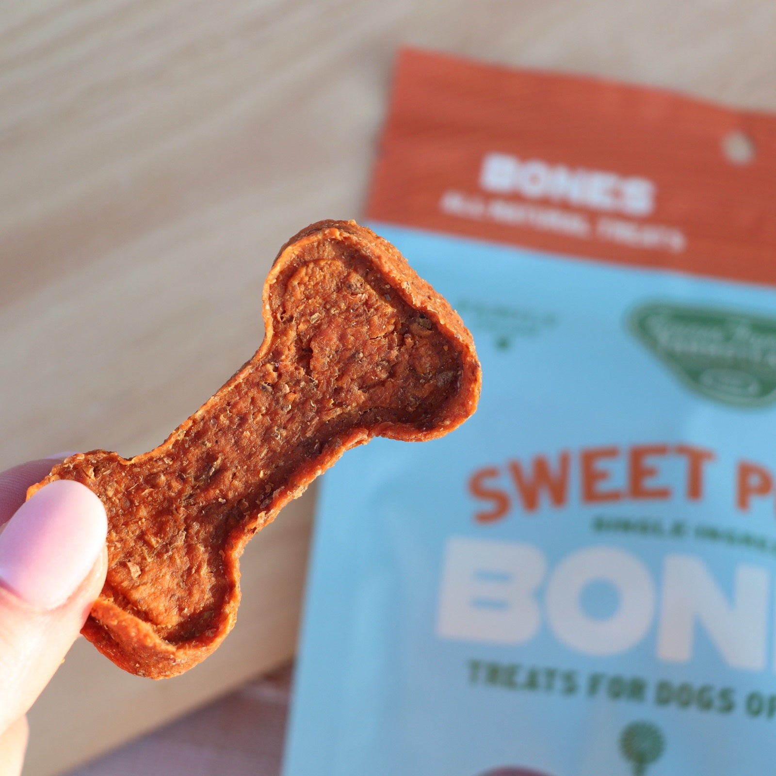 Hand holding a bone-shaped sweet potato treat